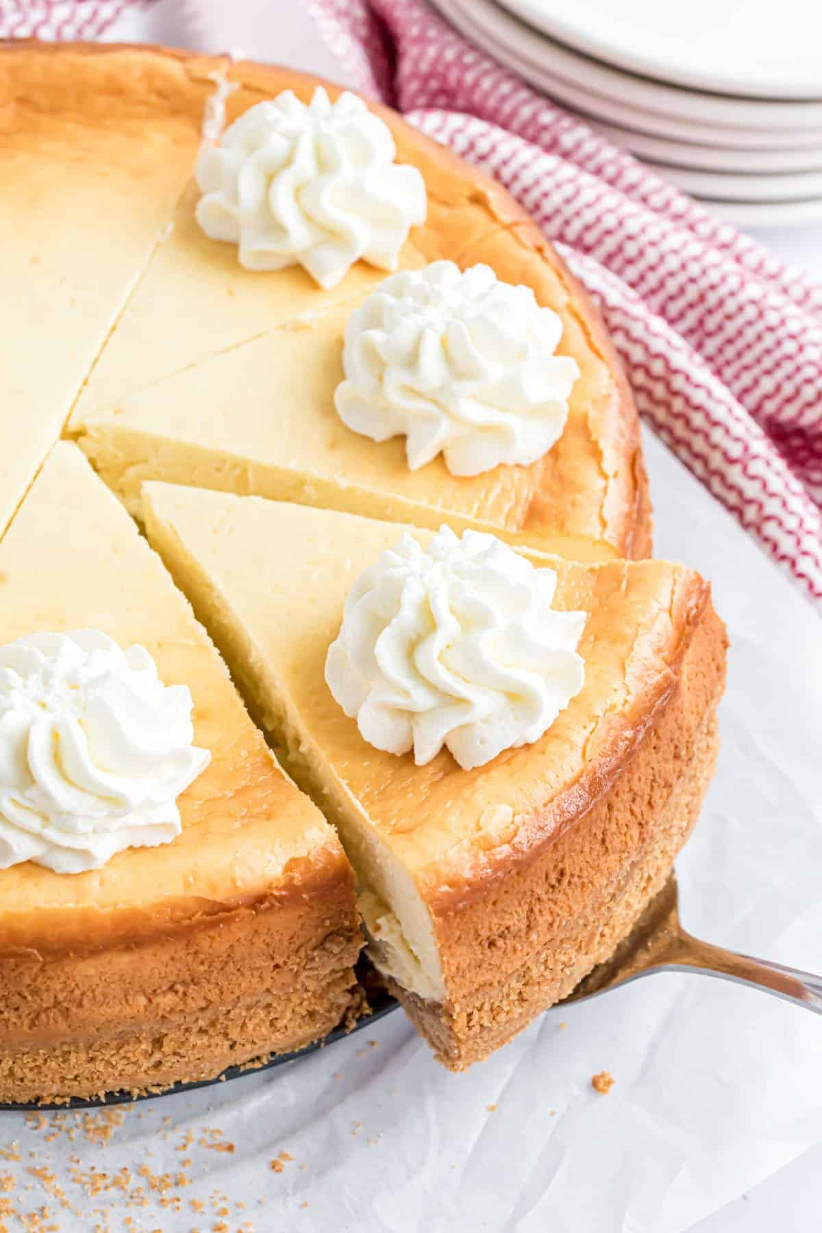 Cheesecake sliced with dollops of whipped cream on top.