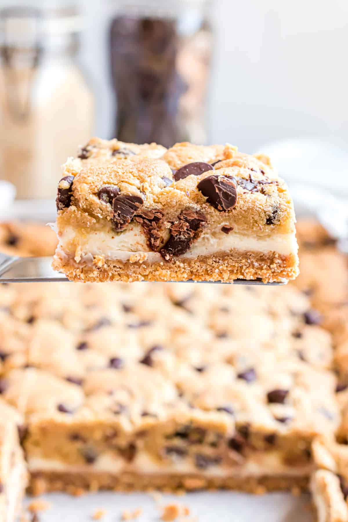 Chocolate chip cheesecake bar on a spatula being removed from pan.