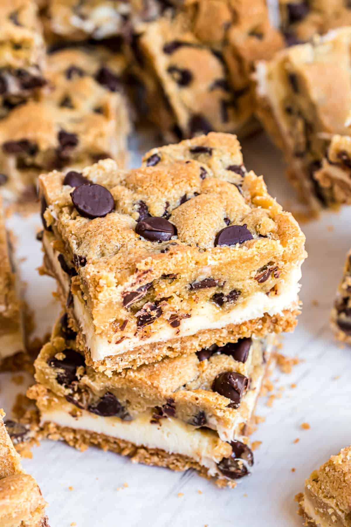 Chocolate chip cookie bars with cheesecake filling stacked on top of each other.