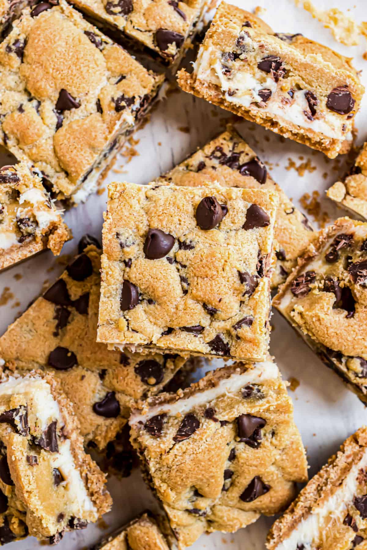 Chocolate chip cheesecake cookie bars arranged on parchment paper.