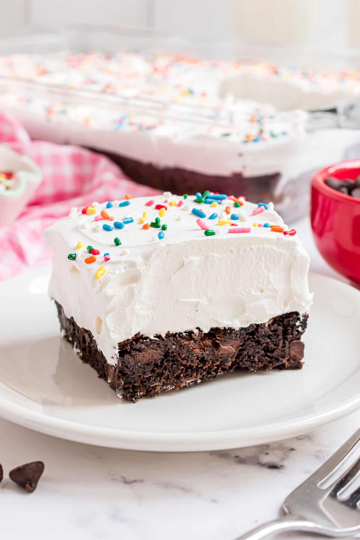 Slice of chocolate cake with cool whip on top.