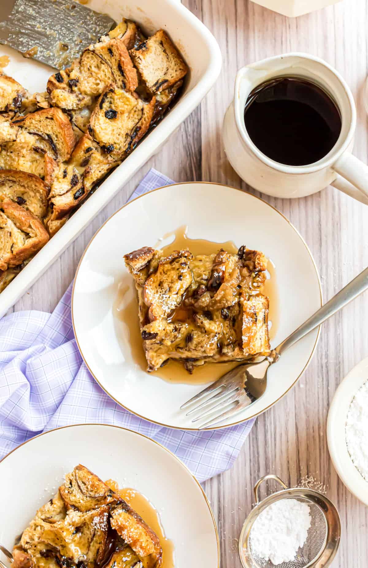 Slices of french toast casserole served with syrup and powdered sugar.