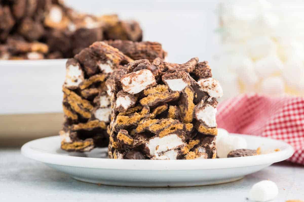 Two indoor s'mores bars with marshmallows, chocolate, and graham crackers rest on a white plate.