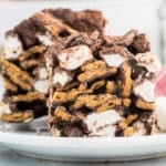 Close-up of two indoor s'mores bars with chocolate, marshmallows, and graham crackers stacked on a white plate.