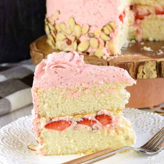 This gorgeous, from scratch, Strawberry Almond Cake recipe features a moist almond layer cake with strawberry buttercream. Fresh sliced almonds and strawberries to added flavor and texture!