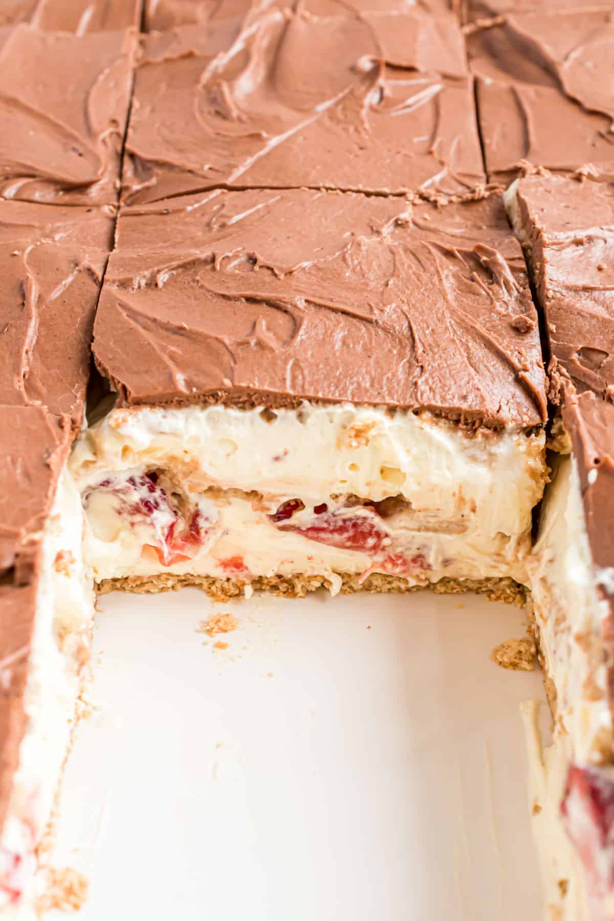 Strawberry eclair cake with one slice removed out of baking dish.