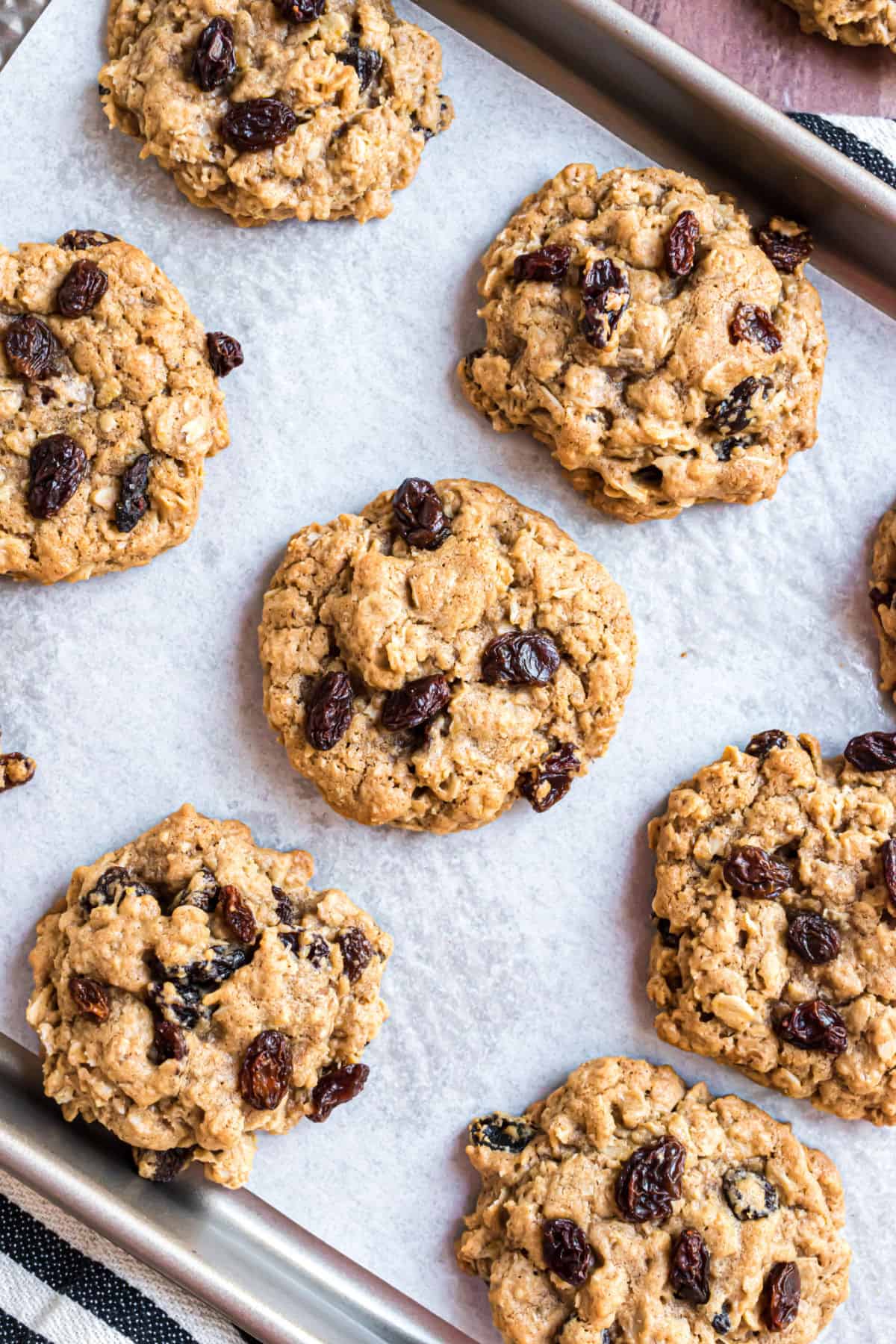 Soft and chewy oatmeal raisin cookies on a parchment paper lined cookie sheet.