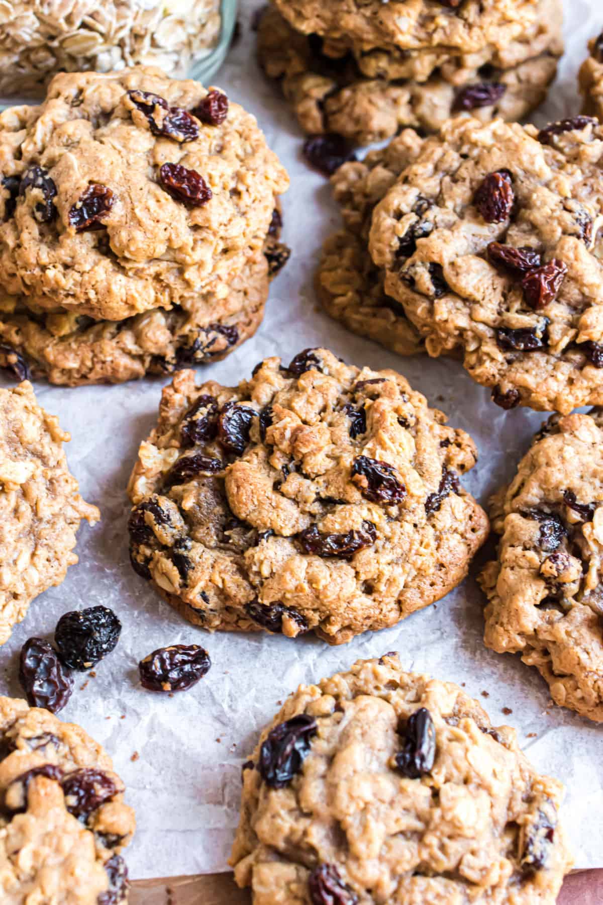 Thick oatmeal raisin cookies stacked on parchment paper lined cookie sheet.