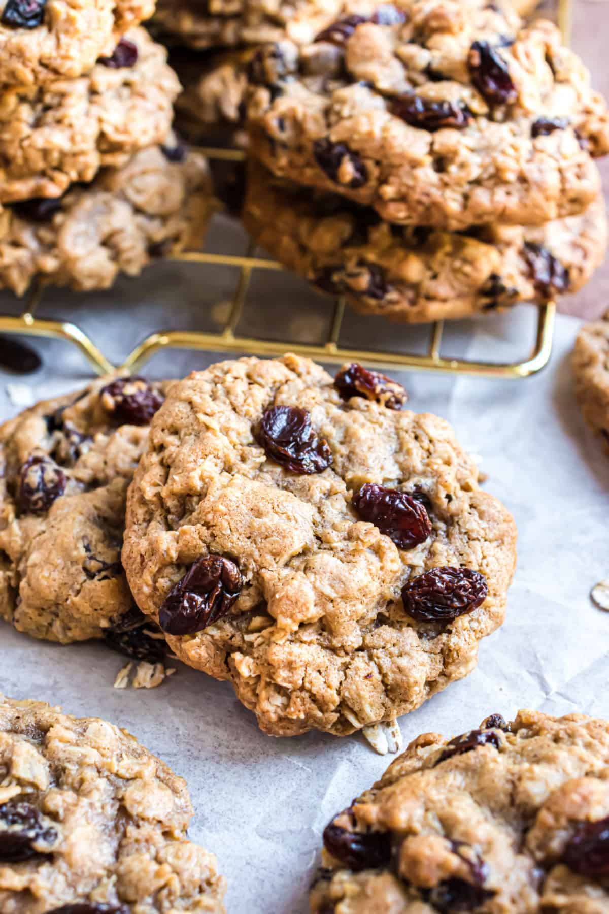 Oatmeal raisin cookies stacked on parchment paper.