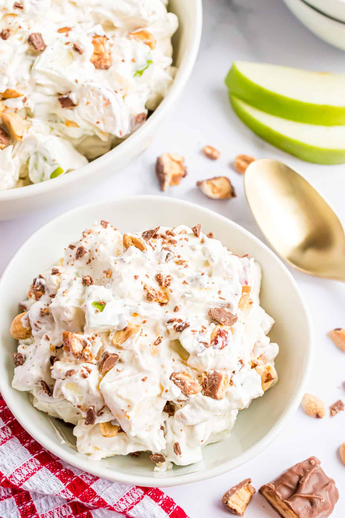 Apple salad with Snickers in a serving bowl with peanuts.