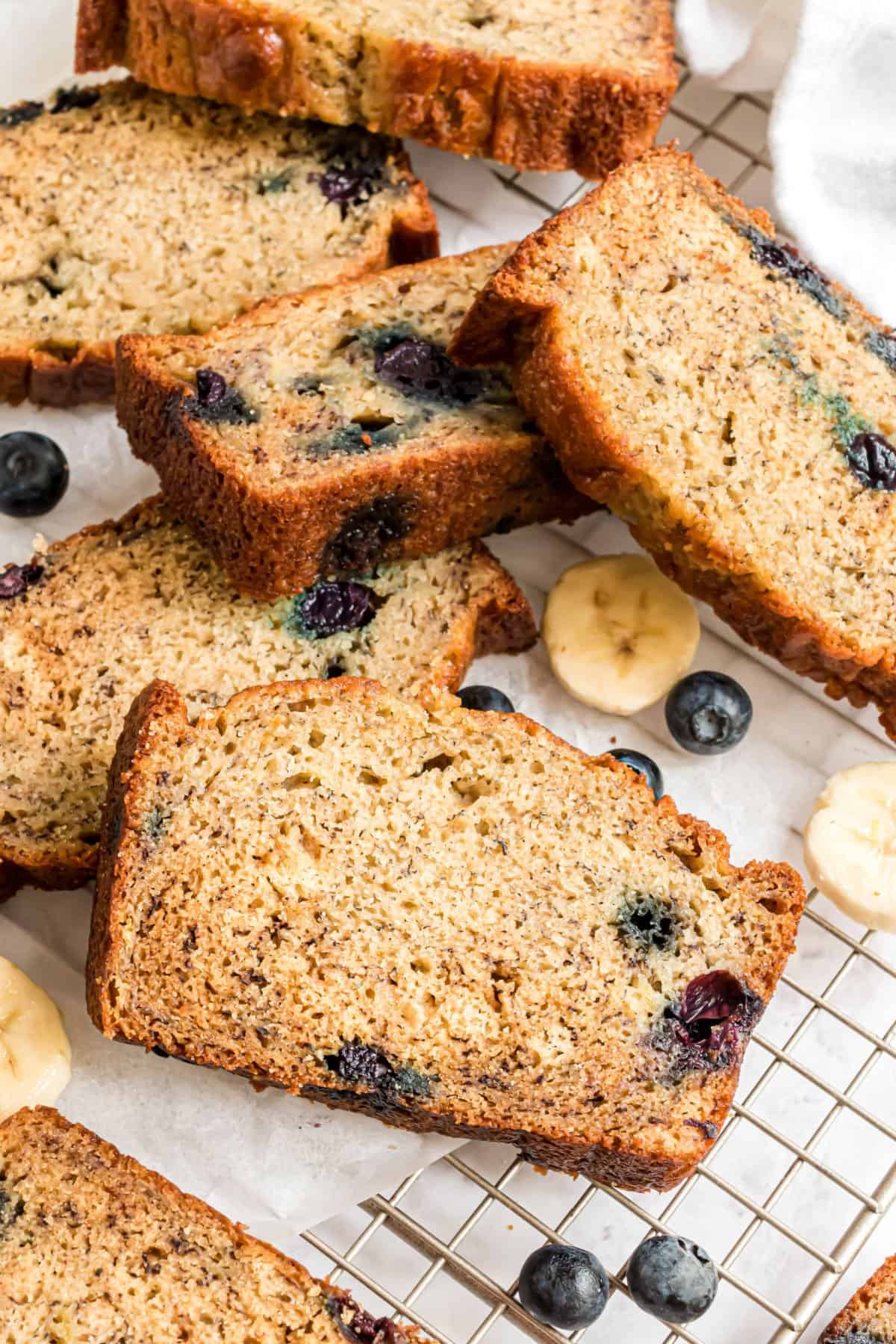 Slices of blueberry banana bread on wire cooling rack.