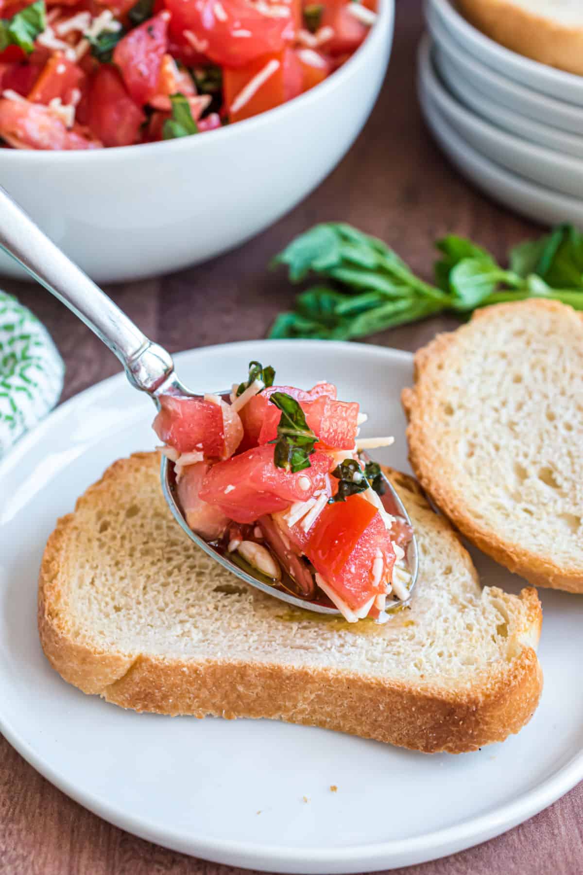 Bruschetta being scooped onto slices of bread for toasting.