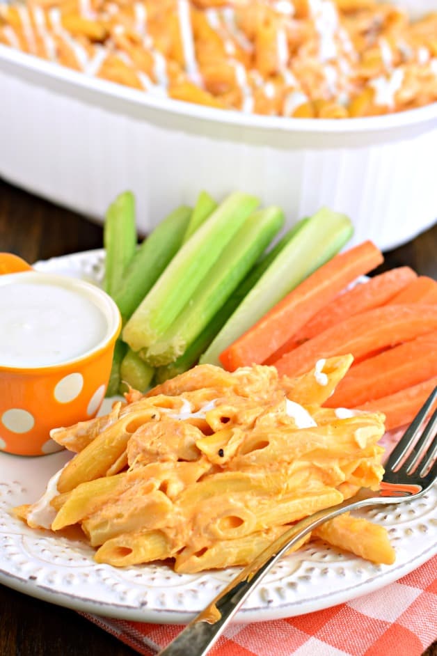 Buffalo pasta served on a white plate with carrot and celery sticks on the side.