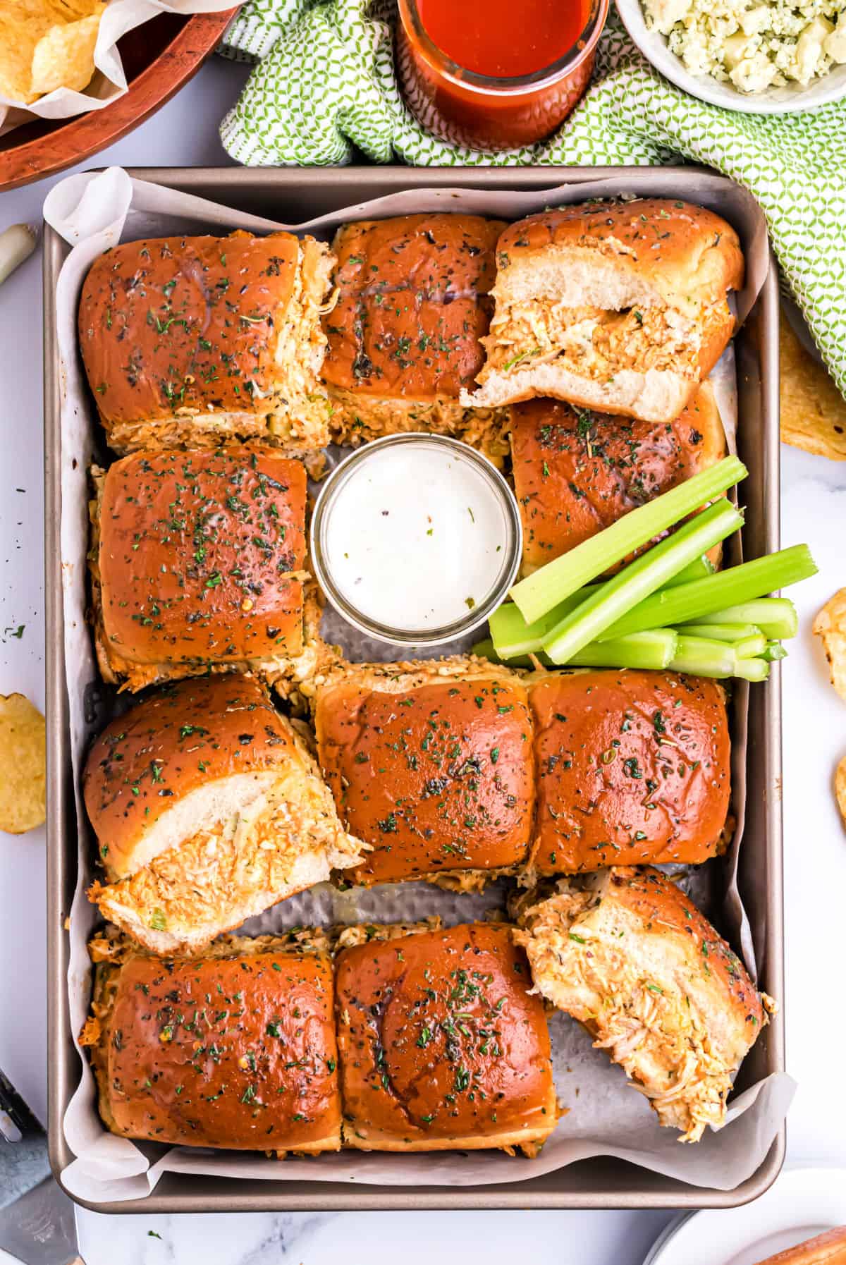 Buffalo chicken sliders baked on a sheet pan and served with blue cheese dressing.