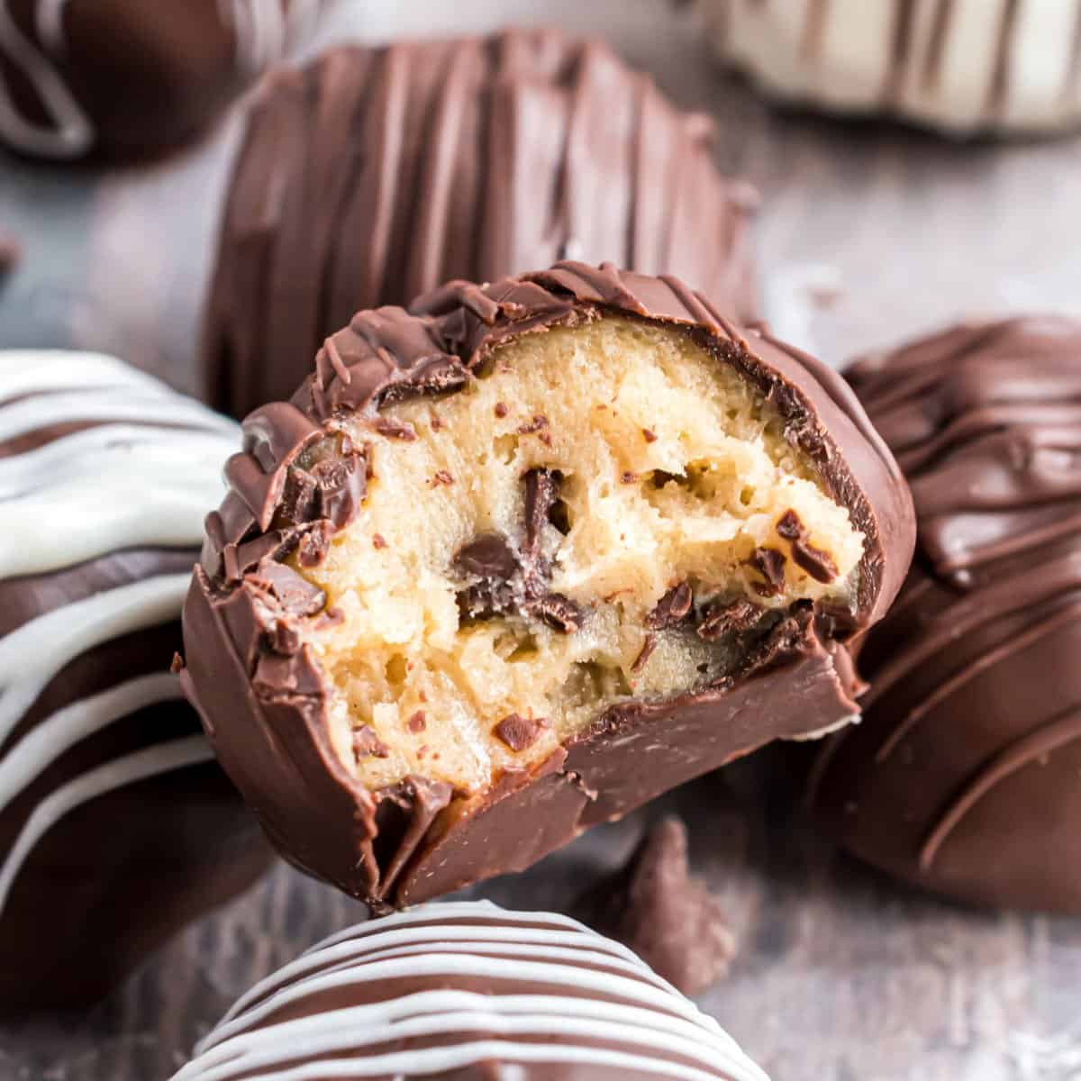 Cookie dough truffles dipped in chocolate with a bite taken out.