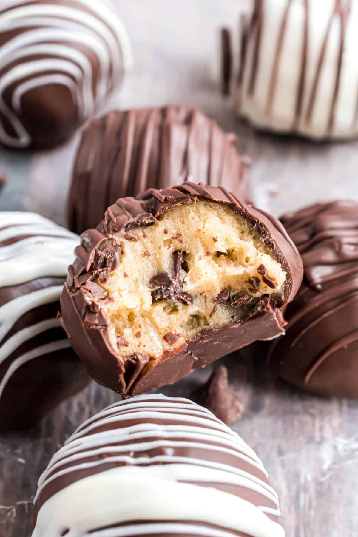 Cookie dough truffles dipped in chocolate with a bite taken.