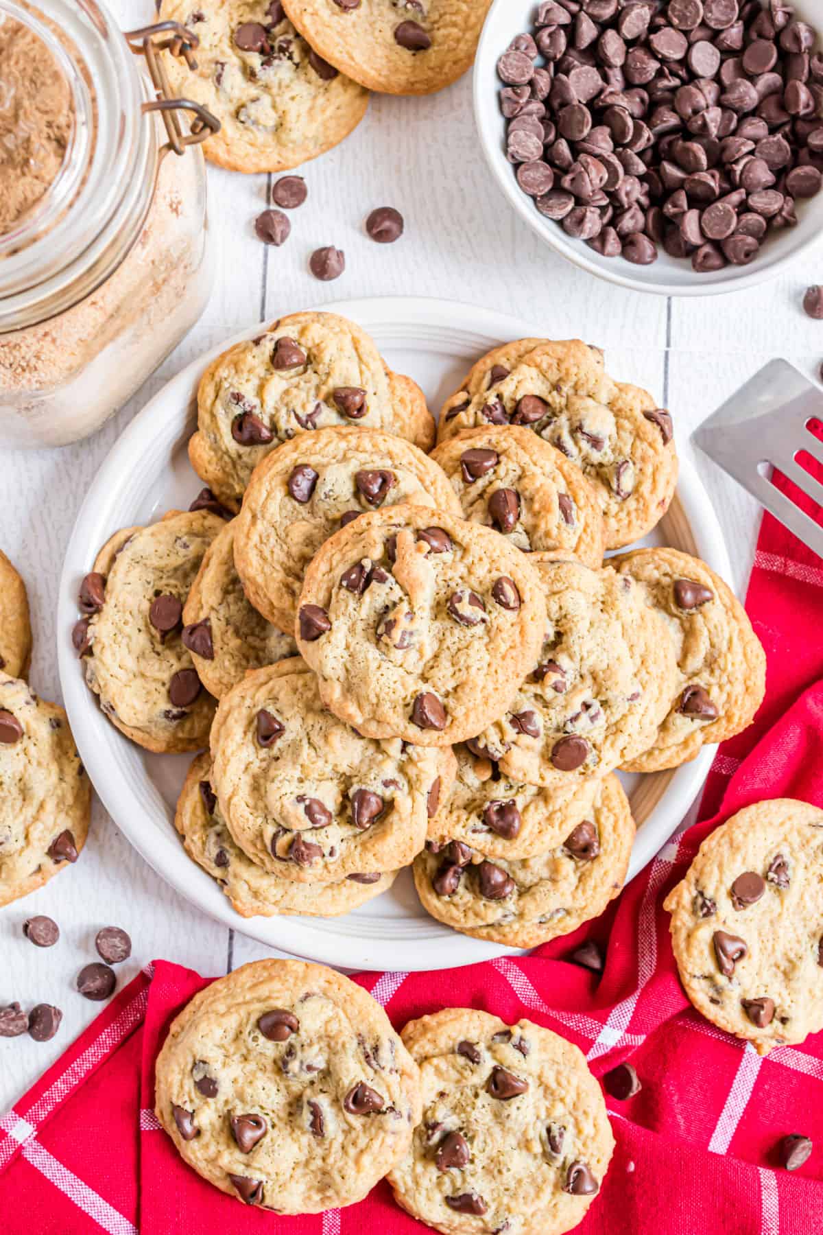 Plate of chocolate chip cookies with some on red linen.