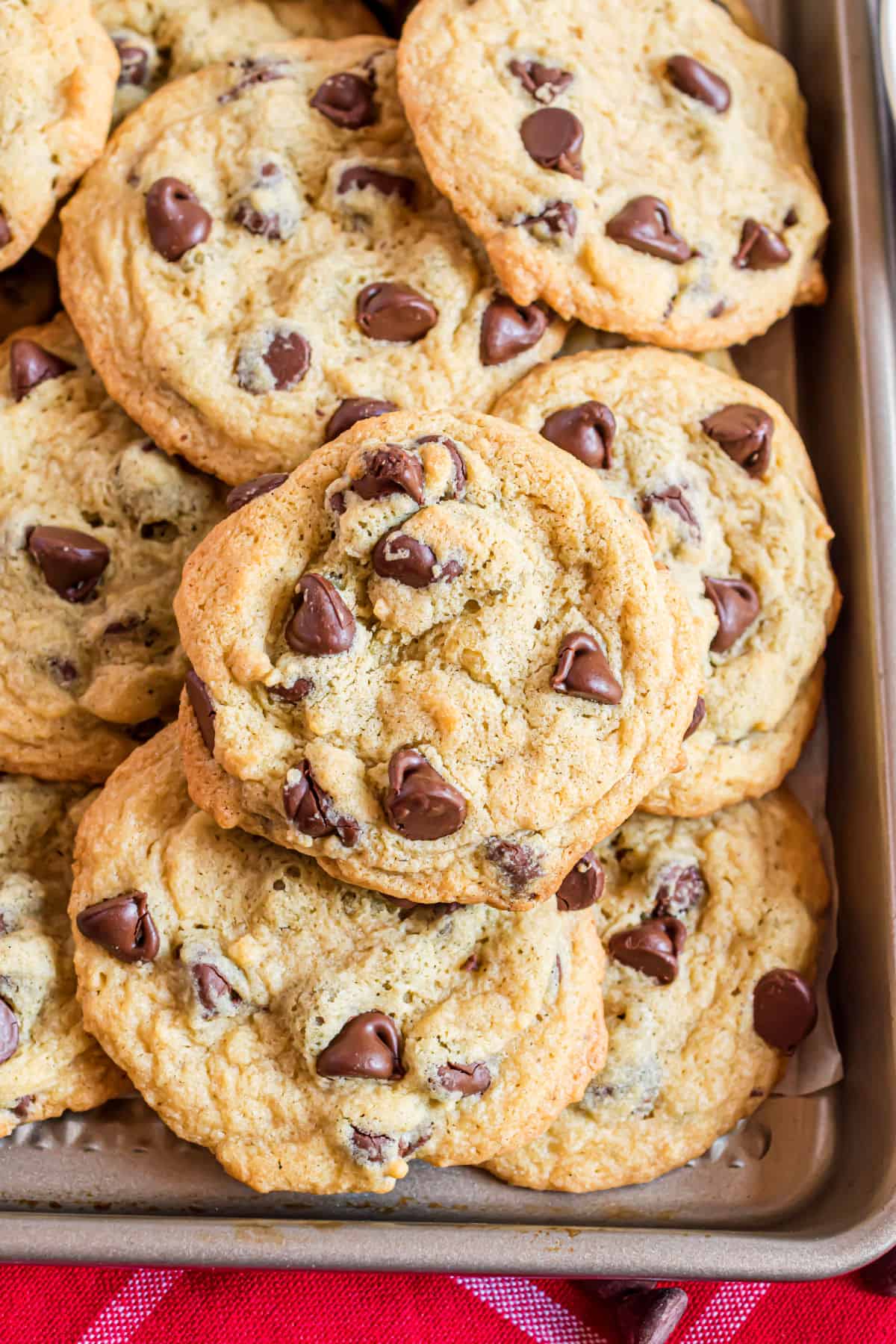 Baking sheet stacked with chocolate chip cookies.