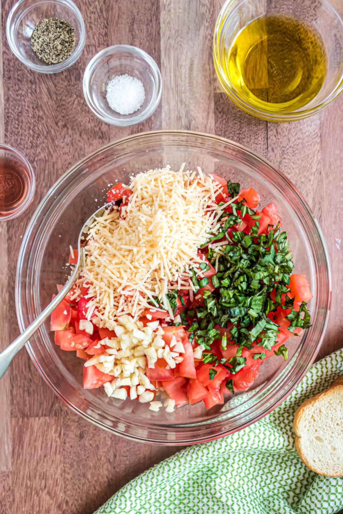 Ingredients for bruschetta in a clear glass bowl before being combined together.