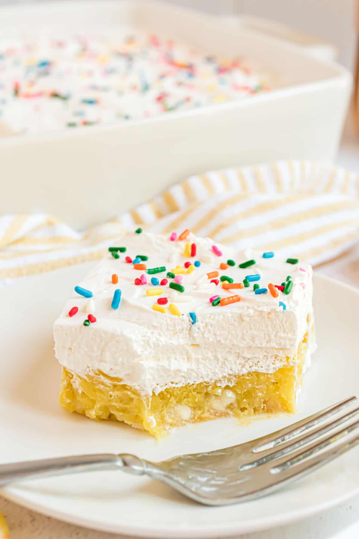 Lemon pudding cake served on a white plate with fork and one bite taken.