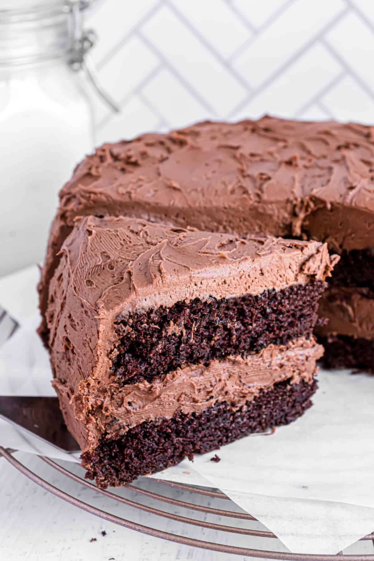 Slice of chocolate layer cake being removed from cake plate with a spatula.