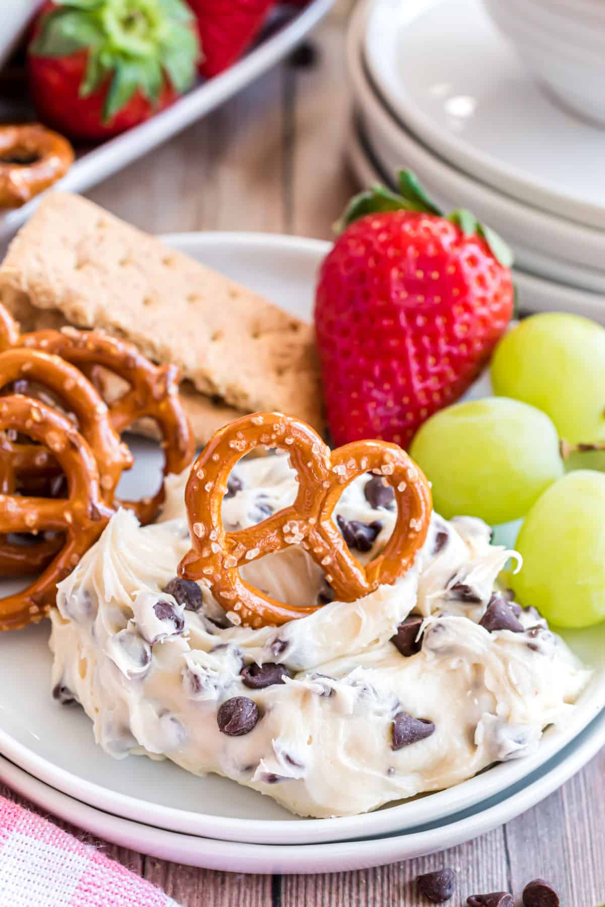 Cookie dough dip on a plate served with pretzels and strawberries.