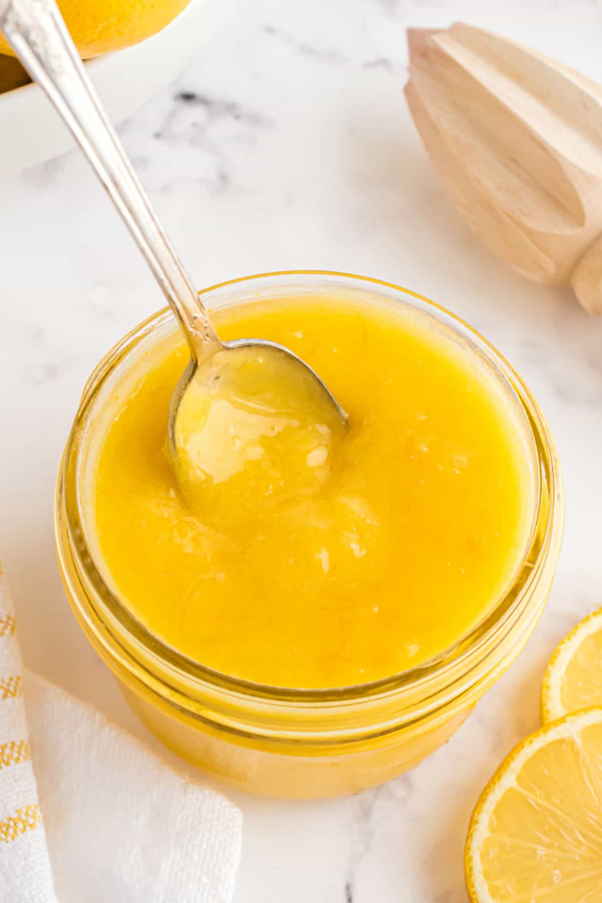 Thick lemon curd in a jar with a spoon.