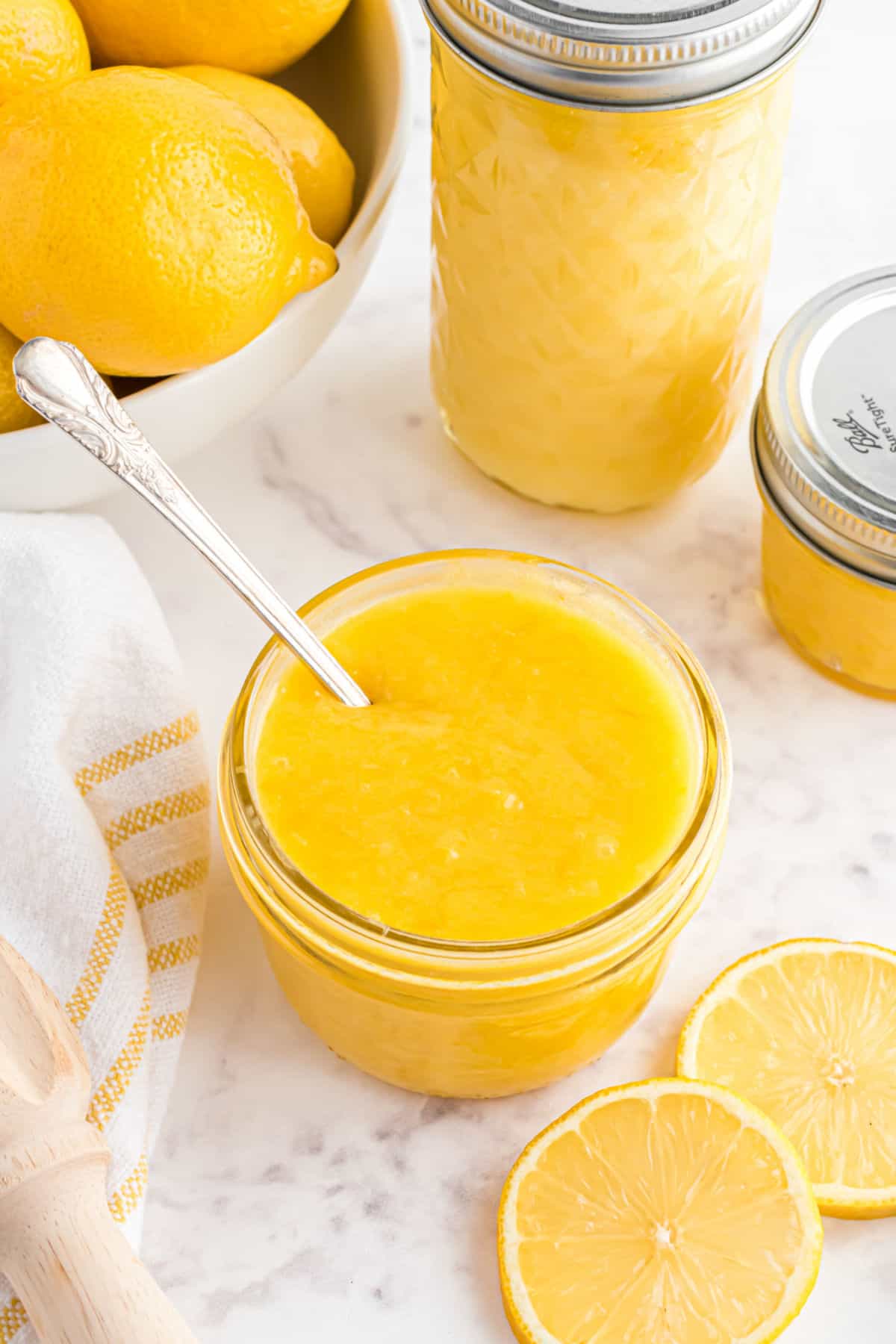 Homemade lemon curd in a small glass jar with a spoon.