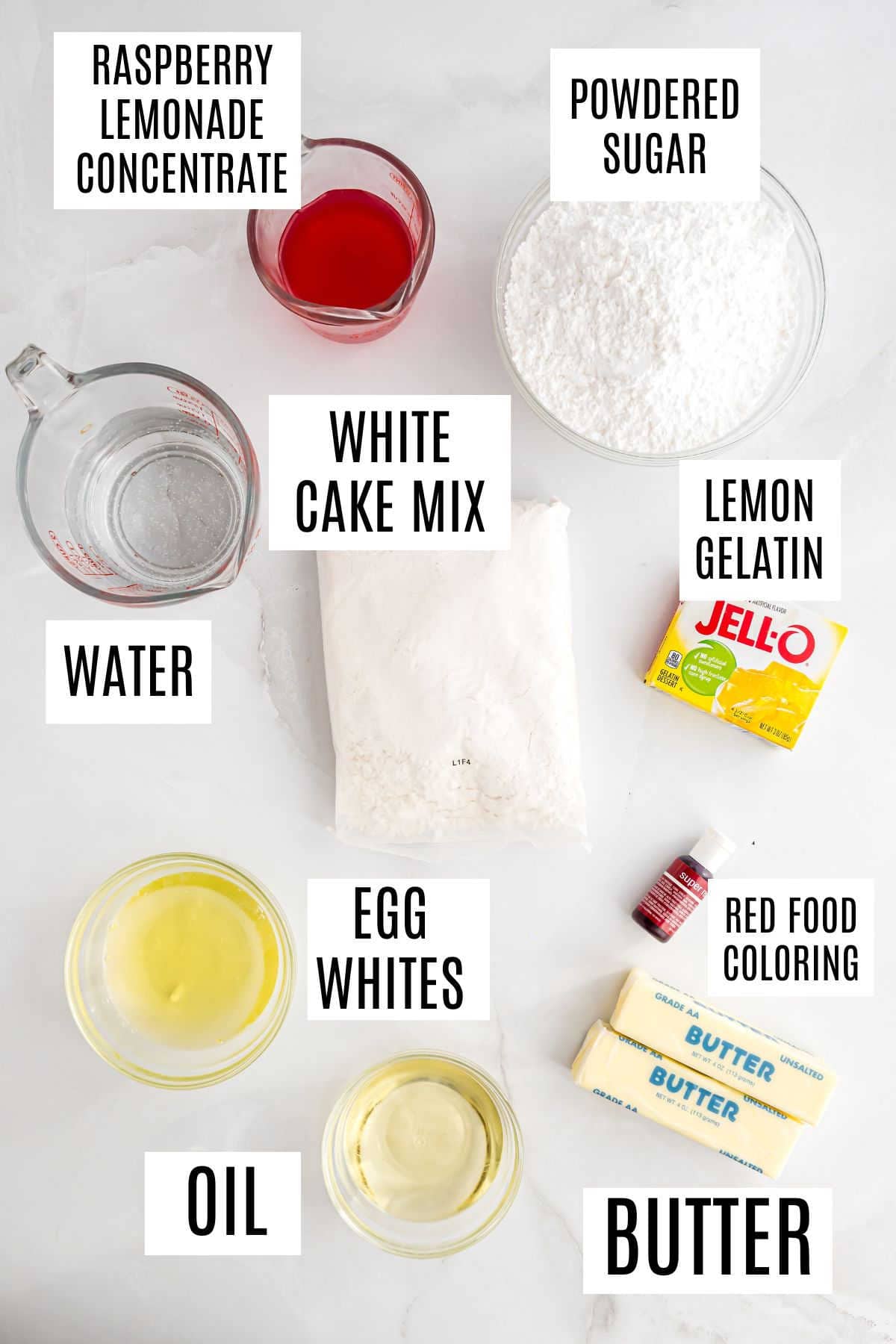 Labeled ingredients for raspberry lemonade cupcakes: white cake mix, egg whites, oil, butter, water, raspberry lemonade, gelatin, sugar, food coloring.