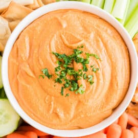 Roasted red pepper hummus in a white serving bowl.