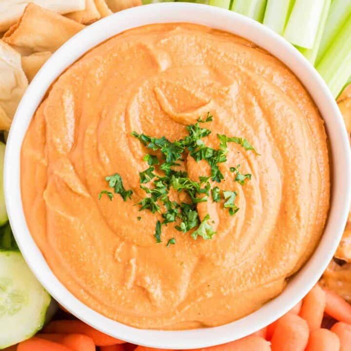 Roasted red pepper hummus in a white serving bowl.