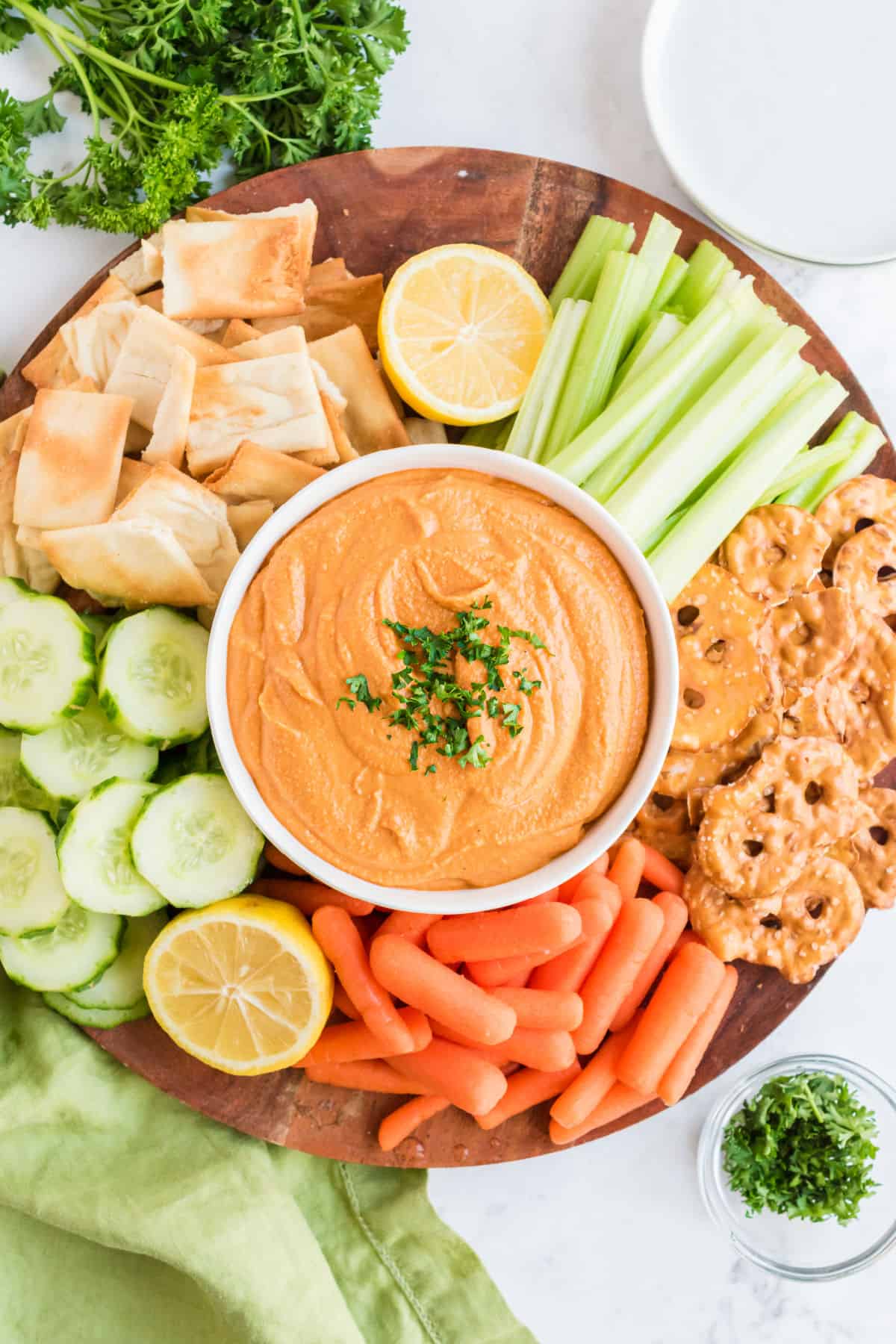 Red pepper hummus served with a platter of fresh vegetables and pita chips.