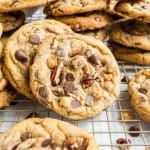 Close-up of caramel pecan chocolate chip cookies stacked on a cooling rack.