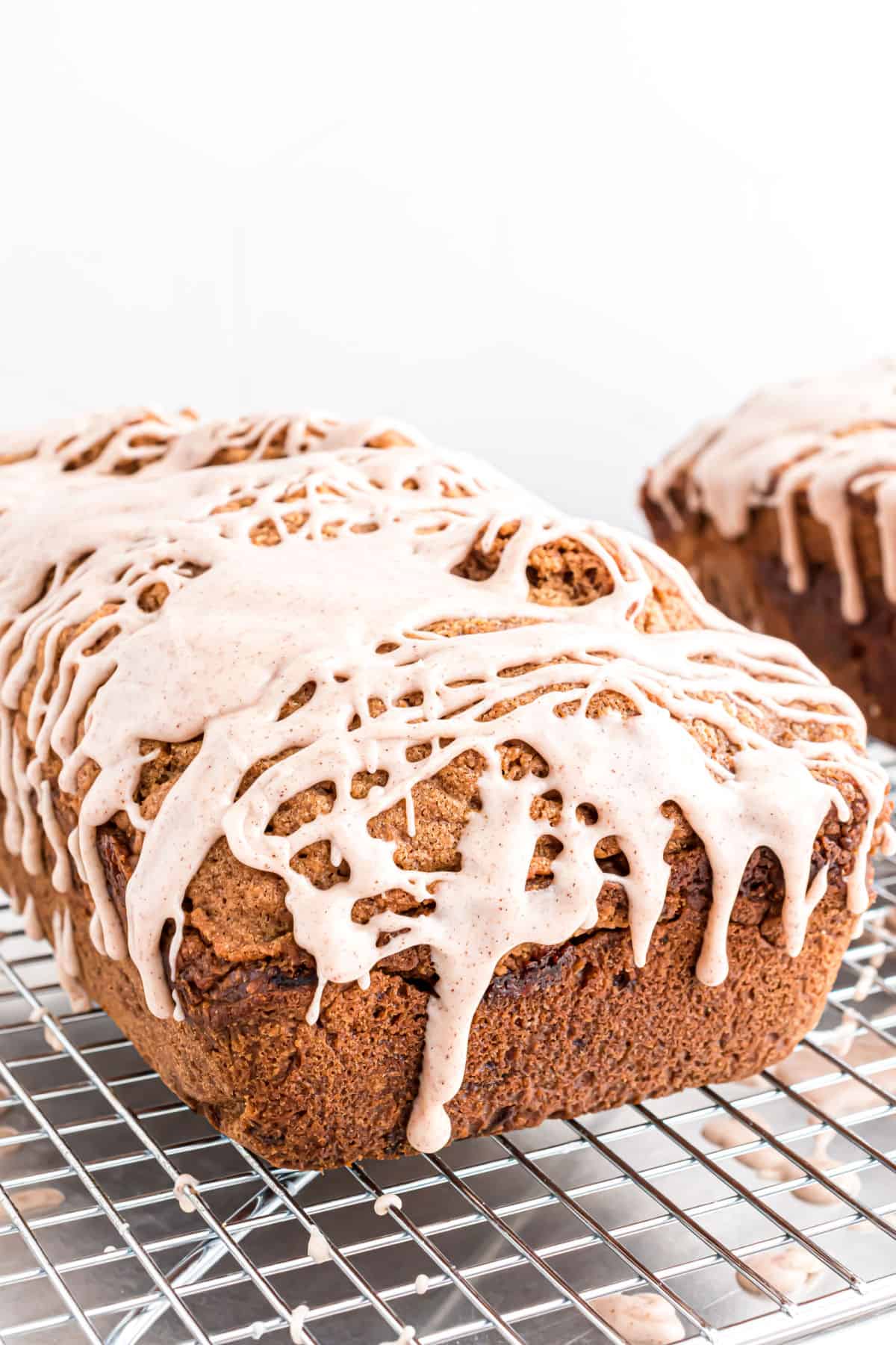 Slice of zucchini bread drizzled with icing on a wire rack.