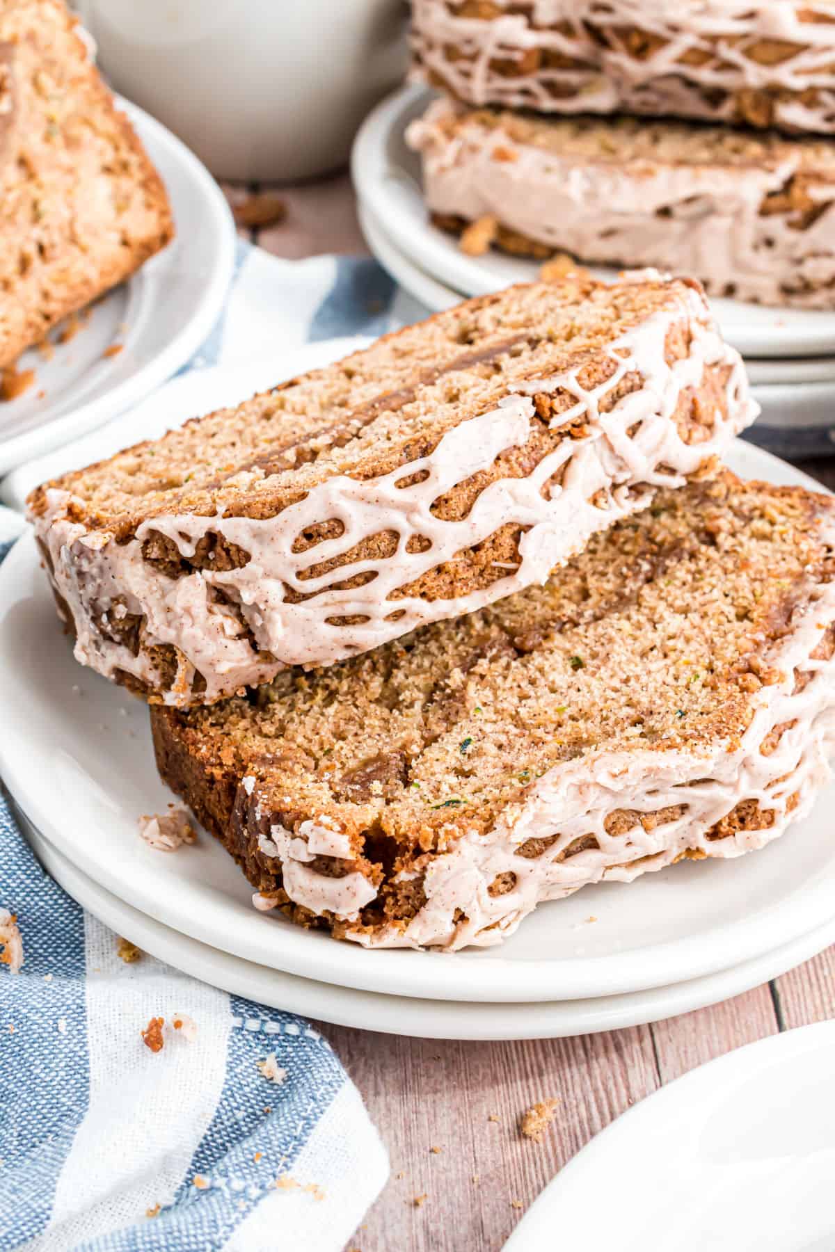 Two slices of zucchini bread on a stack of white plates.