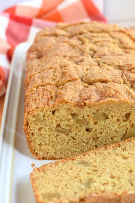 Loaf of apple bread, sliced, on a white serving plate.