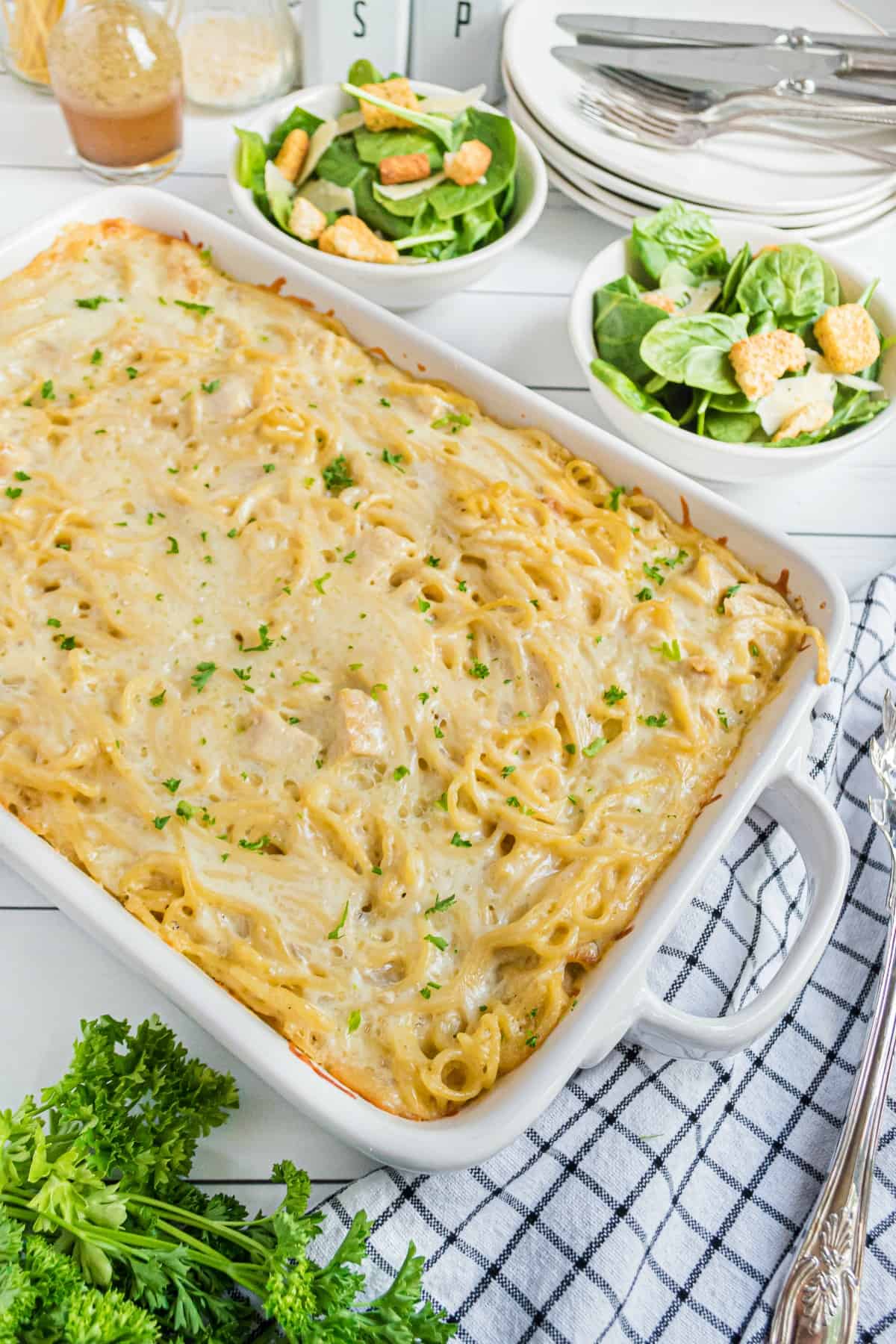 Chicken tetrazzini baked in a white 13x9 dish and served with a green side salad.