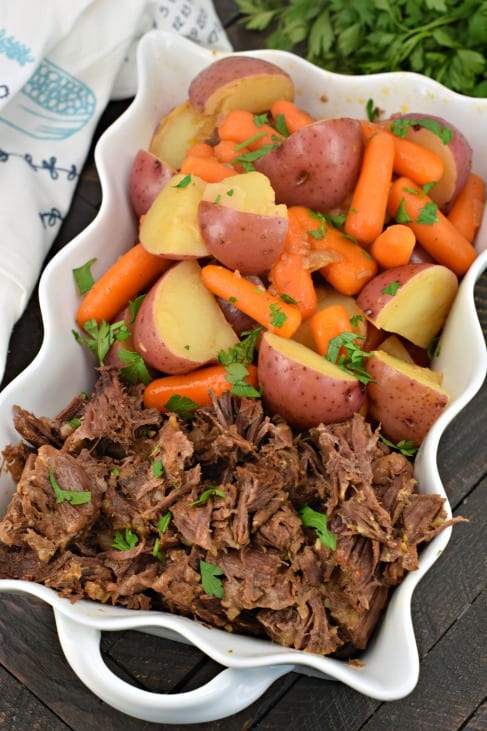 White scalloped dish with pot roast, potatoes and carrots