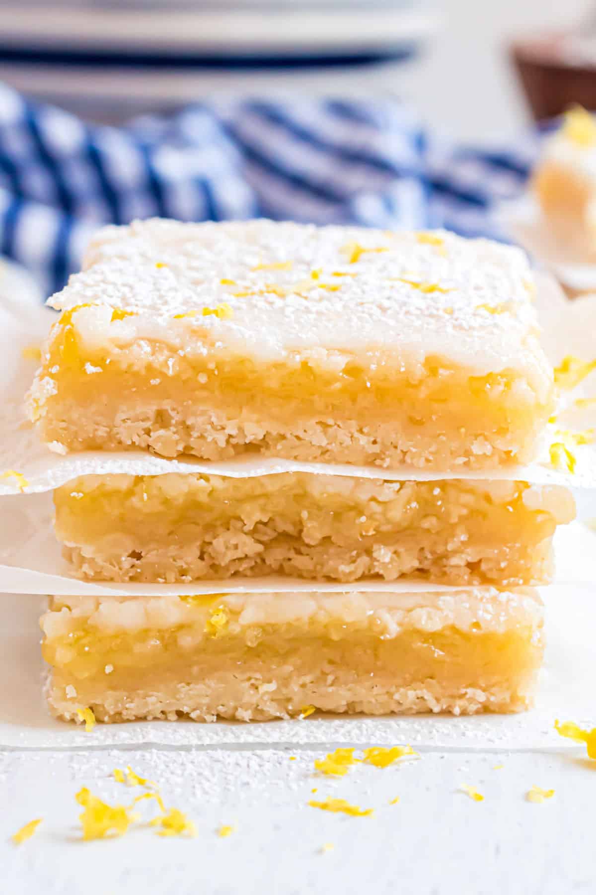 Lemon bars stacked on white parchment paper.