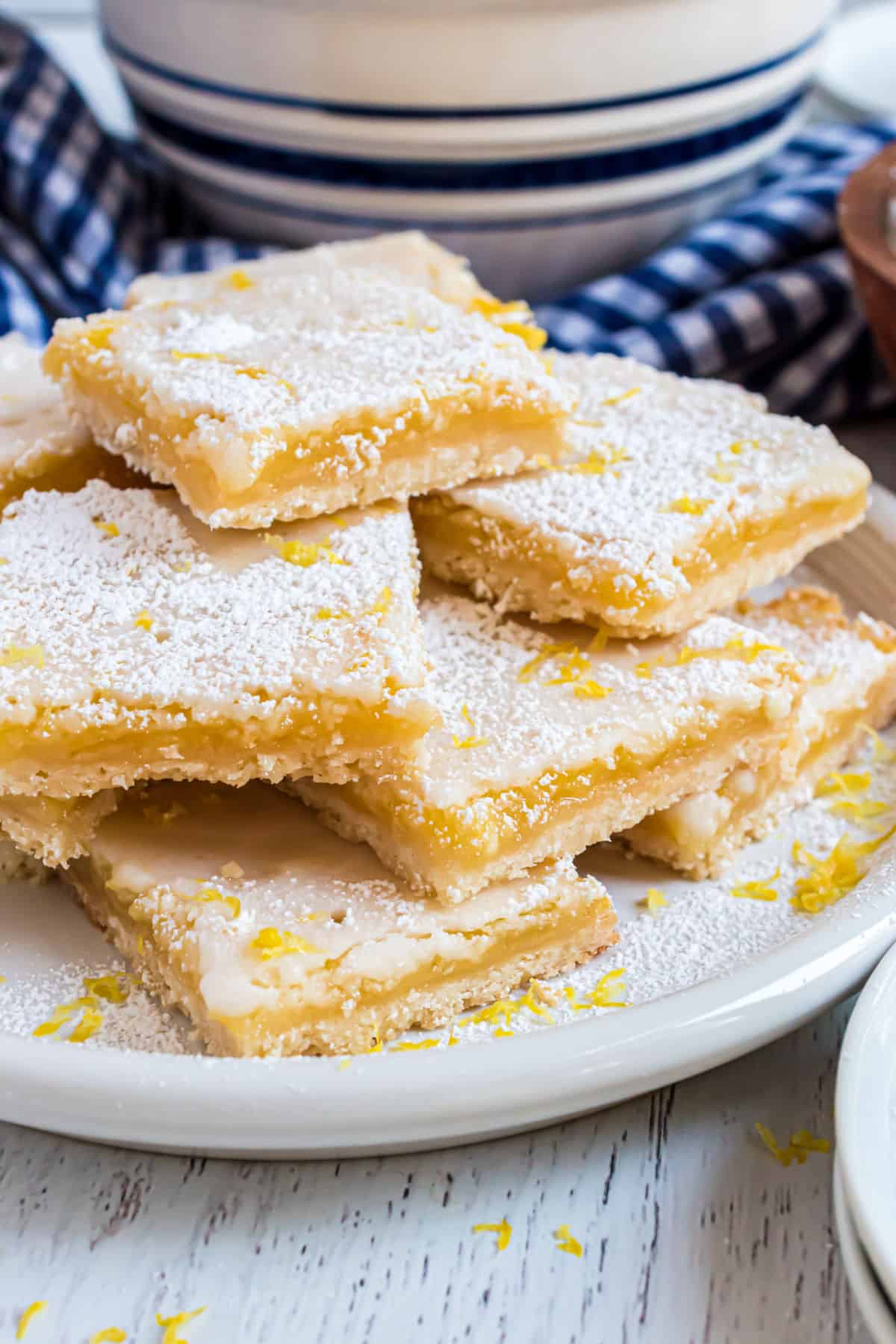 Lemon bars stacked on a white plate.