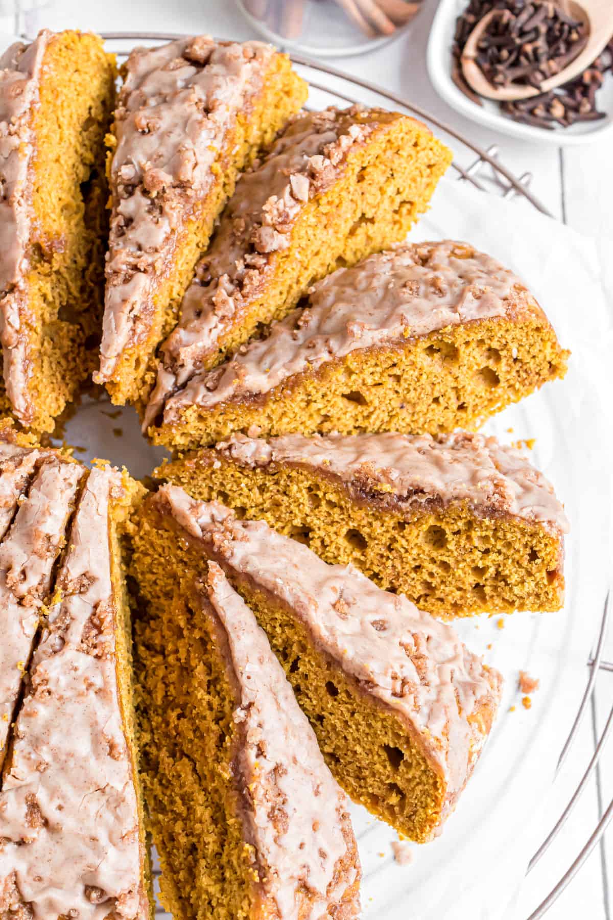 Pumpkin coffee cake with streusel and icing, sliced on a plate.