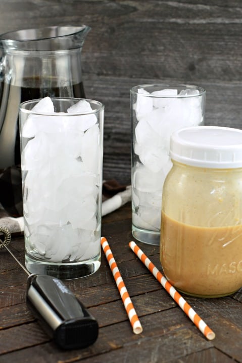 Two glasses filled with ice and a mason jar filled with pumpkin cream.