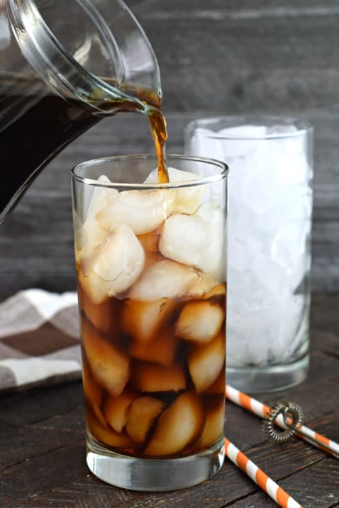 Cold brew coffee being poured into a glass of ice.
