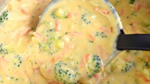 Cheesy broccoli soup being ladled out of pan.