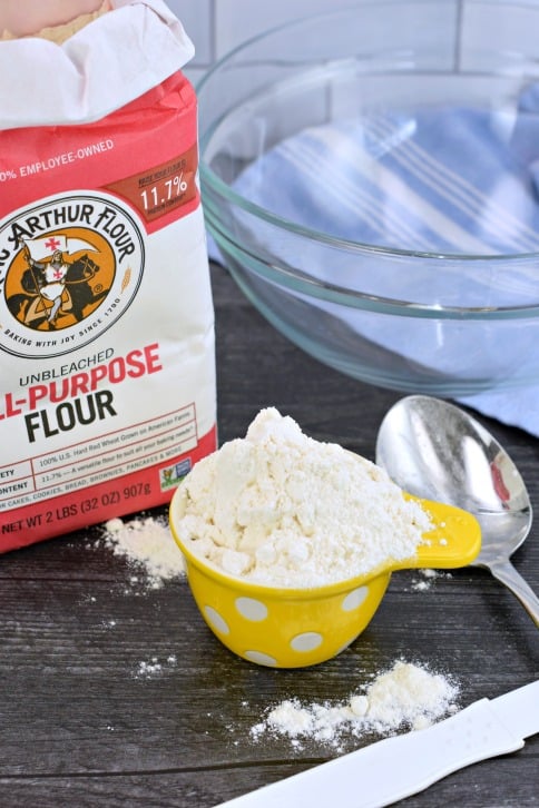 Flour in a yellow polkadot measuring cup.