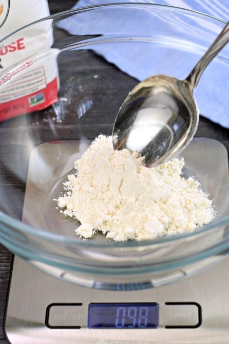 Flour in a clear glass bowl on a scale.