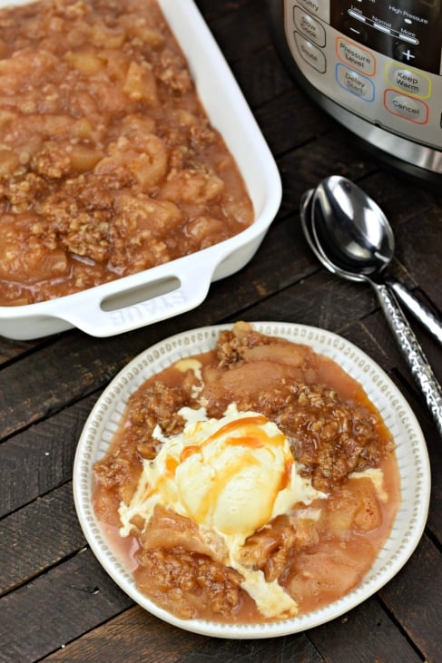 Plate of apple crisp with melted ice cream and caramel sauce.