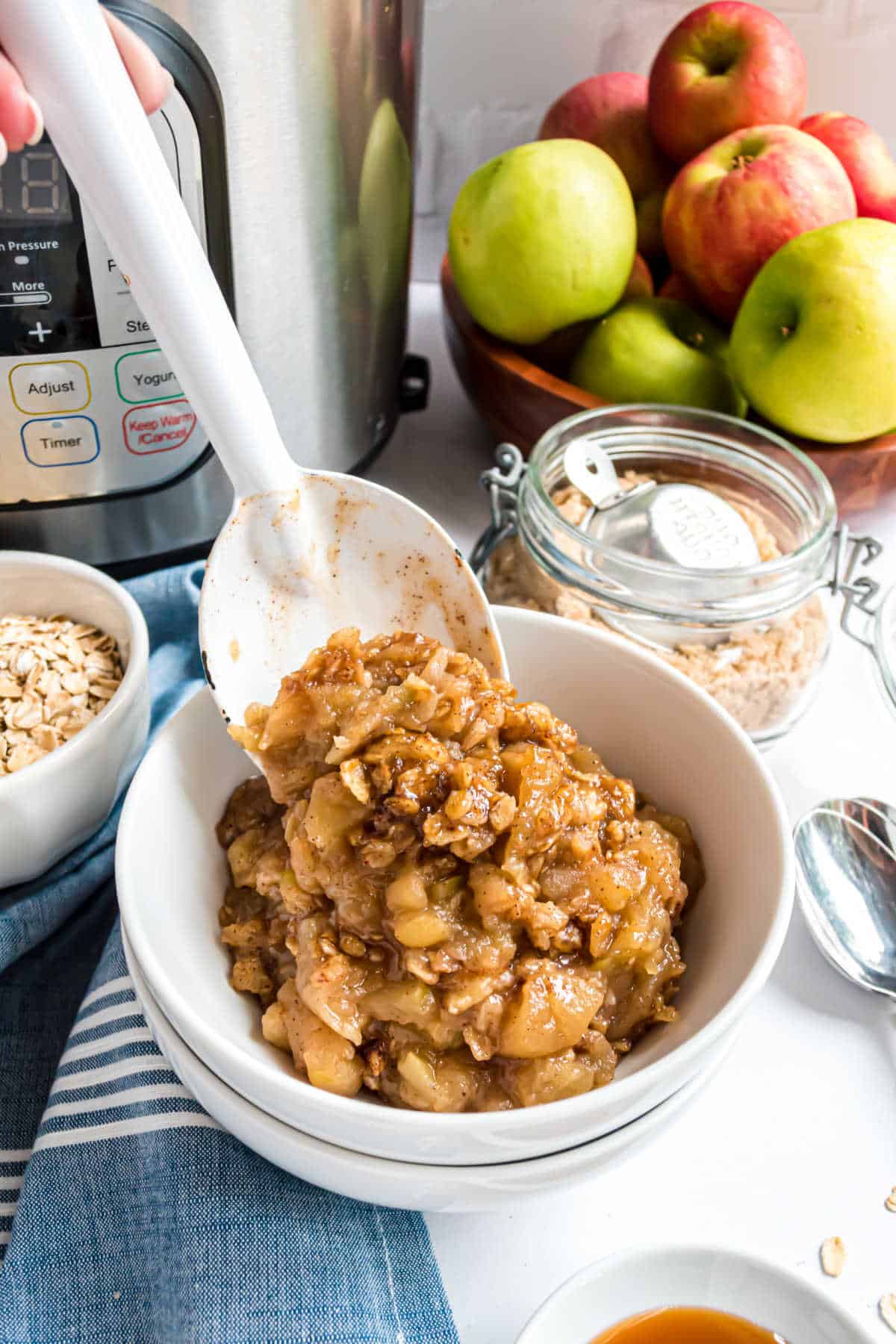 Apple crisp being spooned into a white bowl.