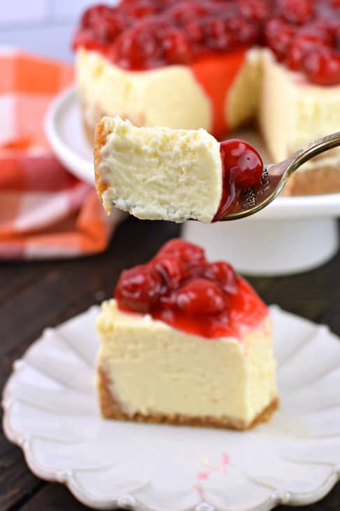 Fork bite of cheesecake with cherry pie filling.