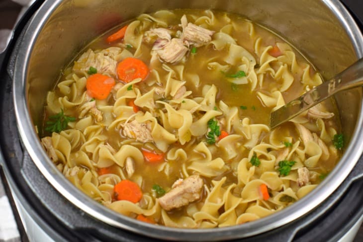 Instant Pot with noodles, chicken, carrots, and broth.